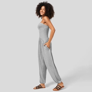 Detail van de getailleerde taille en zijzak van een grijze strapless jumpsuit