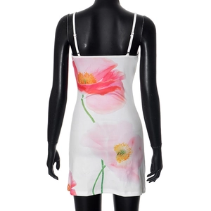 Detail van roze papaverbloemenprint en slanke pasvorm op de witte mini-jurk met bandjes