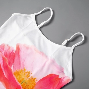 Detail van verstelbare spaghettibandjes en roze bloemenprint op witte mini-jurk