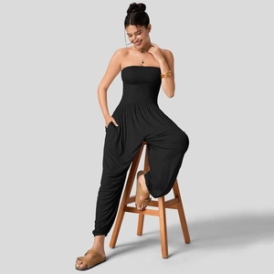 Detail van zwarte strapless jumpsuit met geplooide taille en wijde lantaarnbroekspijp