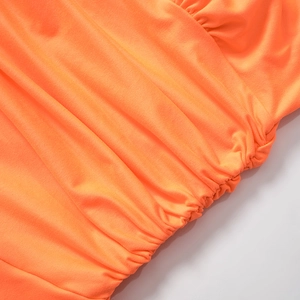 Macro detail of vibrant orange ruched fabric texture and pleated design on dress