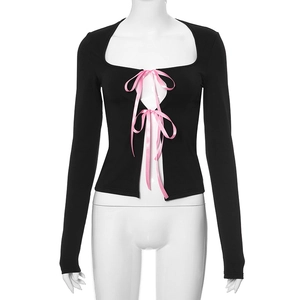 Détail du haut noir à manches longues avec nœuds en satin rose et décolleté carré évidé
