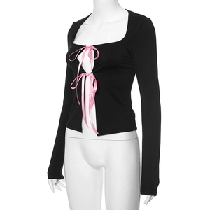Détails des nœuds en satin rose sur le haut en tricot noir à manches longues et col carré