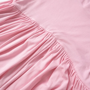 Gedetailleerd macro-overzicht van de geplooide taille op deze roze gebreide jumpsuit