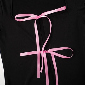 Gros plan sur un haut noir avec des nœuds en ruban de satin rose sur un décolleté carré