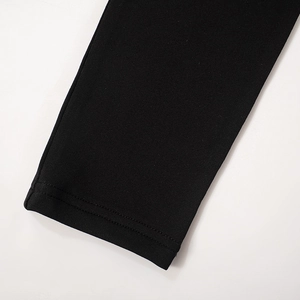 Détail du poignet à double surpiqûre sur un t-shirt noir à manches longues en tricot
