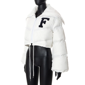 Close-up of white puffer jacket featuring a blue letter F patch and faux fur collar detail