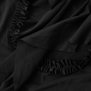 Vue macro du tissu en sergé noir détaillant l'ourlet à volants et la texture plissée