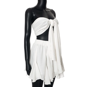 Detail of white chiffon two-piece set featuring a knot-front crop top and pleated mini skirt