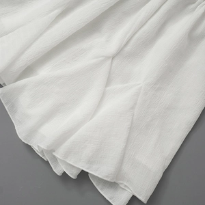 Detailed view of white pleated chiffon fabric texture and ruffled hemline on summer dress