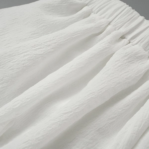 Detailed close-up of white smocked elastic waistband with textured seersucker fabric detail