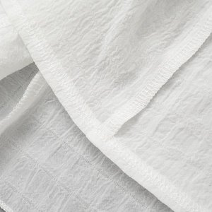Macro detail of white pleated chiffon fabric showing high-quality stitching and texture