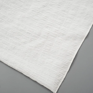 Close-up of white seersucker fabric with small checkered texture and delicate overlock edge