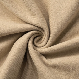 Close-up of beige knitted fabric showing fine texture and soft vertical drape of the dress