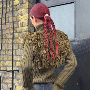 Detail of olive green ribbed sweater showing long fringe tassels on the shoulder and back