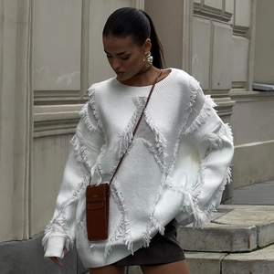 Detail view of the thick white distressed knit sweater with fringe tassel texture