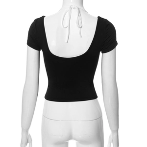 Detail of the backless crop top with white halter neck ties on a black knit shirt