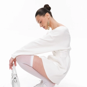 Side view detail of a minimalist white long sleeve mini dress with a fitted waist design