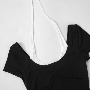 Detail of a black backless crop top featuring a contrast white halter neck strap design