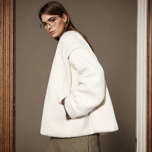 Detailed macro view of white sherpa fabric texture and brown ribbed knit cuff on the sleeve