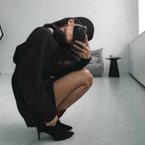 Artistic indoor shot of minimalist black oversized hoodie with stylish high-heeled ankle boots