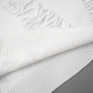 Detail of white knit sweater showing ribbed cuffs and distressed frayed edge texture