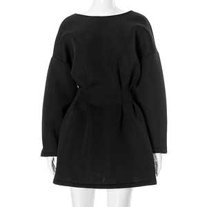 Detail view of black long-sleeve dress featuring pleated waist and structured fabric