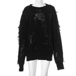 Detail of distressed black knit sweater showing irregular holes and fringe texture
