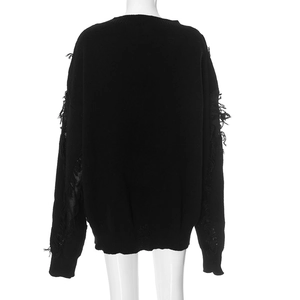 Detail view of the distressed knit texture and long fringe on black oversized sweater