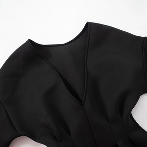 Detailed close-up of the V-neck design and precise stitching on the black mini dress