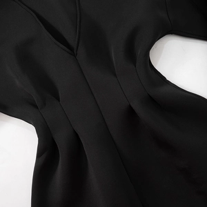 Detailed view of the deep V-neckline and elegant pleated waist of this black dress