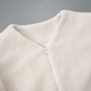 Detailed close-up of cream fleece jacket neckline with zipper and plush fiber texture