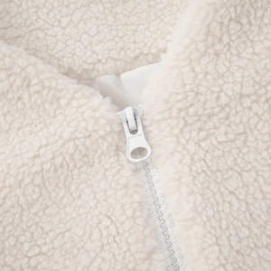 Macro detail of high-quality white plastic zipper on a cozy cream sherpa fleece jacket