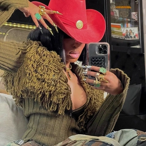 Detail of green fringe knit cardigan with wide-brim red cowboy hat and gold rings