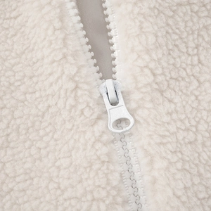 Macro detail of ivory sherpa fleece fabric texture with matching resin zipper closure