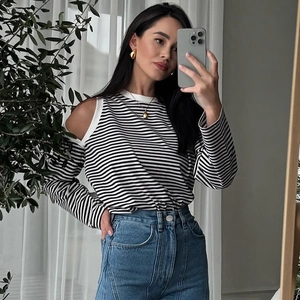 Detail of off-the-shoulder cutout design on a black and white striped long sleeve top