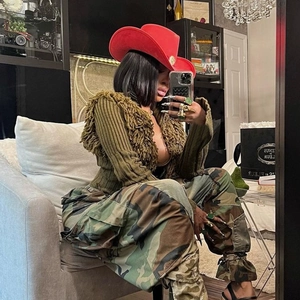 Detail of red wool cowboy hat with green tassel knit cardigan and camo cargo pants