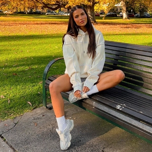 Detail view of cream oversized hoodie with exposed seam stitch and adjustable drawstring