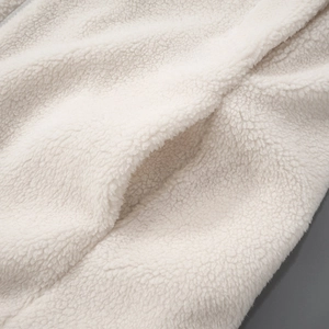 Close-up of ivory sherpa fleece fabric texture and side pocket stitching detail