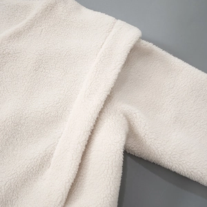 Detailed macro view showing the soft ivory fleece texture and stitching of the winter jacket