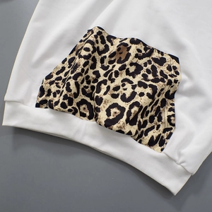 Detailed close-up of a white sweatshirt featuring a leopard print pocket and ribbed cuffs
