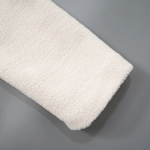 Close-up of premium white sherpa fleece material with thick curly plush texture detail