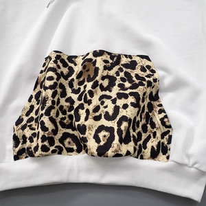 Detail of white hoodie featuring leopard print front pocket and ribbed hem texture