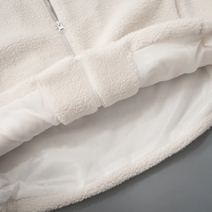 Detailed macro shot of the cream sherpa jacket showing inner lining and zipper hem quality