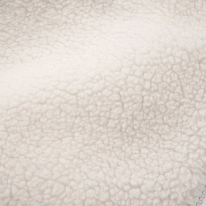 Detailed macro view of soft cream Sherpa fleece fabric showing curly plush texture