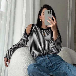 Detail of a cold-shoulder striped knit top with textured fabric and metallic accessories