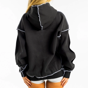 Detailed back view of oversized black hoodie with white contrast stitching and ribbed cuffs