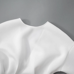 Detailed close-up of the clean stitching and round neckline on a white mini dress