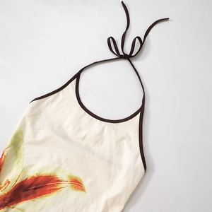 Detail eines flach liegenden Neckholder-Tops mit Blumenmuster und braunem Saum