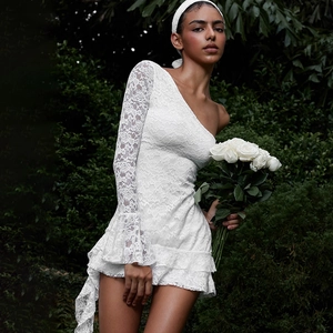 Detailed view of white floral lace texture on a one-shoulder tiered ruffle mini dress